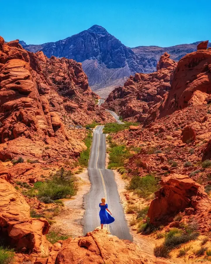 Two-lane road curving between red rock walls on Mouse's Tank Road, the main scenic route on the Valley of Fire map, Nevada
